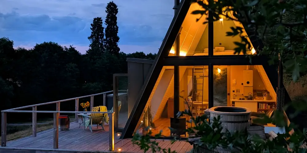 The A Frame lit up at dusk with its glass end wall glowing