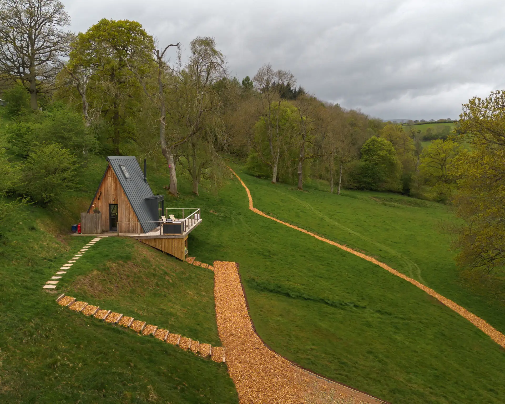 Aerial view of the A Frame cabin on a green hillside with a gravel path