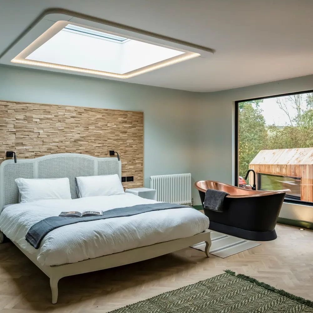 Bedroom with a skylight above the bed and a copper bath beside it