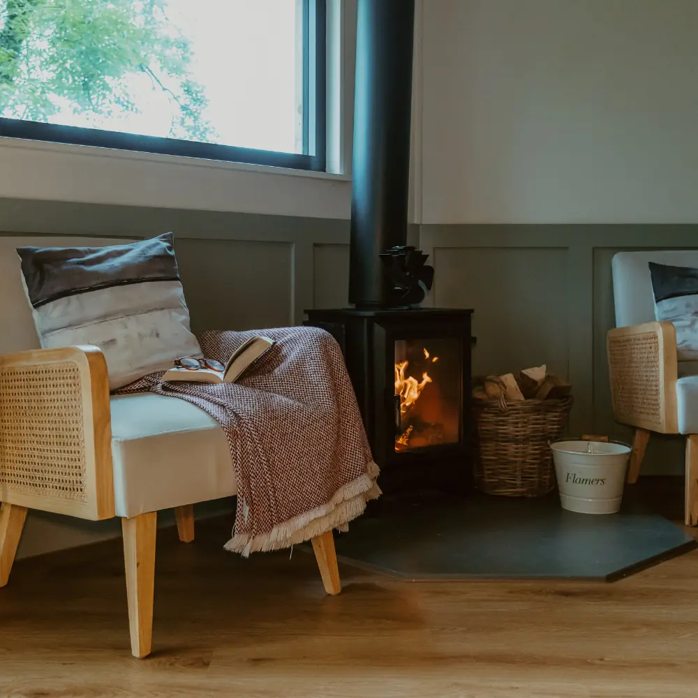 A rattan armchair beside the Treehouse wood burner